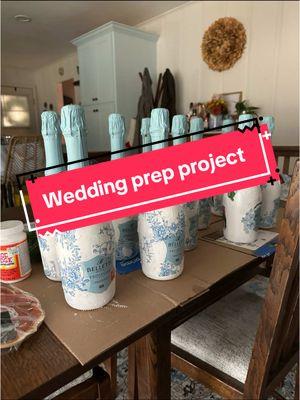 Less than 3 weeks until the wedding! ✨🙌🏻💍   A fun little project for the wedding day. We are using these for the morning of the wedding and throughout the week.  ✨4 coats of white acrylic paint ✨napkins/wallpaper for the layer ✨ mod podge  ✨ ribbon for bow  I taped off the bottles, painted them and let dry betweem each layer. Cut out the napkins, mod podged and let dry for 24 hours!  #weddingprep #weddingprojects #proseccoprojects #wedding #weddingtiktok #crafty #bachelorette 