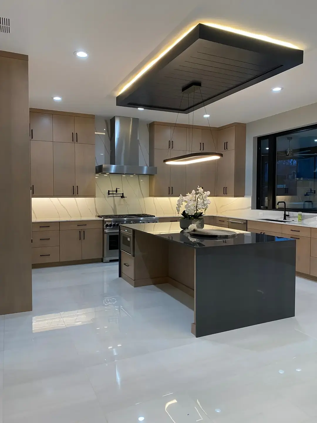 Everything in this kitchen is designed to impress, from the high-end appliances to the large, spacious island that centers the space.  The dramatic lighting above creates the perfect atmosphere for any cooking session, making this kitchen an inviting space for everyone. Builder:  Sapphire luxury homes Agent: @sabakatto  Photography: @Adrian Kizy  #customkitchen #kitchendesign #kitchendecor #homebuilder #customhomebuilder #kitchenideas