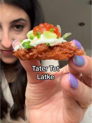 A tater tot latke!!! Honestly one of the best latke variations out there… recipe below‼️ Ingredients: -2 large russet potatoes, peeled  -1/2 large yellow onion -2 eggs  -1/2 cup freshly shredded sharp cheddar cheese -1/4 cup matzo meal -2 tsp kosher salt -vegetable oil, for frying  -sour cream, for serving -green onions, finely sliced, for serving -chives, finely chopped, for serving -apple sauce, for serving Directions: -Using a box grater, grate the potatoes and onions on the large holes. Place them in a cheese cloth or dish rag. Into a large bowl, wring out the liquid from the potatoes and onions. Allow the liquid to sit for about 10 minutes, then discard while leaving the starchy bottom layer.  -Into the bowl with the starch, add the shredded potatoes and onions, eggs, sharp cheddar, matzo meal, and kosher salt. Mix to evenly combine.  -Onto a baking sheet, spread the potato mixture out about 1/2 inch thick. Shape it into a large rectangle then place it into the freezer for about 20 minutes so it’s slightly set. Once slightly set, remove from freezer and cut into small squares (the size of tater tots).  -Heat about 1 inch oil in a large skillet over medium high. Place the latke squares in, being careful not to overcrowd, and fry until deep golden brown on both sides. Once done, move to a paper towel lined plate. -Serve immediately with sour cream, onions & chives, and apple sauce. Enjoy!  #latke #latkerecipe #Recipe #EasyRecipe #jewishfood #hanukkah #hanukkahfood 