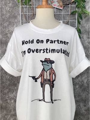 Froggy fashion for the win! 🐸✨ #HoldOnPartner #OverstimulatedVibes #CowboyFrog #FunnyApparel #UniqueDesigns #ComfyAndCool #WesternStyle #FrogLovers #HoodiesSeason #SweatshirtWeather #TshirtGoals #StayCozy #ExpressYourself #GiftIdeas