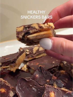 let’s make healthy snickers bars 🍫 ingredients: (makes 16 squares) • 12–16 fresh medjool dates (pitted) • ¾ cup (210g) runny roasted peanut butter • ¾ cup (110g) roasted peanuts or roasted almonds, chopped • 2 tbsp coconut oil • 4.4 oz (125g) 70% dark chocolate, chopped • 2 tbsp peanut butter or coconut oil (extra) • optional: flakey sea salt instructions: 1. grease and line a 20cm square baking tin with parchment paper or use a silicone tray of the same size 2. break open the dates, remove pits, and spread them flat. lay the dates open-side down to cover the base of the baking tin. press them down evenly using your fingers or a spoon to form a solid layer without gaps. set aside 3. add peanut butter and coconut oil to a small saucepan. melt over low heat, stirring constantly to prevent burning. once smooth and combined, remove from heat and let cool for 10 minutes until slightly thickened 4. pour the peanut butter mixture over the date layer and spread it evenly. sprinkle the chopped nuts over the top. freeze for 1 hour or until firm 5. melt the chocolate with the extra 2 tbsp peanut butter or coconut oil using a double boiler or microwave in 15-second intervals, stirring in between. pour the melted chocolate over the slice, spread evenly with a spoon, and sprinkle with sea salt if using 6. freeze for 30 minutes until firm. use a sharp knife warmed under hot water to cut into 16 squares 7. enjoy straight from the freezer or fridge. it melts quickly on warm days. store in an airtight container in the fridge or freezer for up to 3 months • • • • #hea#healthysnackss#desserts#EasyRecipei#quickrecipei#snickersbara#healthysnickersbaro#proteinsnacks#easysnacka#healthydessertu#glutenfreea#healthydessertsa#healthytreatsr#viralrecipesg#veganrecipesa#healthychocolatebarg#highproteinm#homemadesnickersa#healthycandyi#dairyfreedessert #healthier 