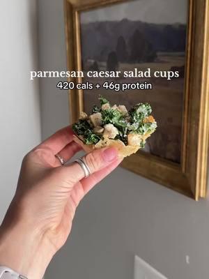 parmesan caesar salad cups recipe ⬇️ 420 cals + 46g protein for the entire recipe!  1/2 cup parmesan cheese 2/3 cup kale (or you can use romaine) 4 oz fully cooked chicken (I used just chicken from trader joe’s) 1.5T ken’s light caesar dressing (thinned mine with water to stretch it!) 5 croutons salt and pepper  preheat oven to 350°. spread parmesan on a parchment lined baking tray into two circles (around 3" wide). bake for 5ish mins until cheese is just melted. immediately take out of the oven and place each circle over and upside down muffin tray.  finely chop your kale and chicken. drizzle on your dressing and crunch your croutons into the mix. add some salt and pepper to taste. stir and divide the salad evenly between the two cups! that’s it - hope you love this as much I do!  ✨tag me @lexingtonbrewer if you make it!!  #busymommeals #highproteinmeals #lunchidea 