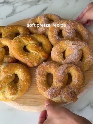 Soft pretzels recipe below 🥨🎀🤍✨ Ingredients: -1 1/2 cups warm water  -2 1/4 teaspoon instant yeast (one packet)  -1 teaspoon salt -1 tbsp sugar  -4 cups flour  -8 cups water  -4 tablespoon baking soda -1 large yolk  -1 tbsp water  -salt  -cinnamon sugar  1. In a large bowl mix together your water, yeast, salt and sugar. Allow to sit for 1-2 minutes while proofing. Add in your flour and mix well in either a standing mixer with a hook attachment or with a wooden spoon. Knead in the mixer or by hand for 4-5 minutes until the dough is soft and smooth and easily pulls away from the bowl.  2. Shape dough into a ball, cover with a dish towel and let rest for 20 minutes. Once done resting, cut into 8 pieces. Roll out each one into a long rope, make a teardrop shape, twist the ends once and fold it over to make a pretzel shape. 3. Preheat oven to 450F. Make a baking soda bath by boiling 8 cups of water in a large pot. Once boiling, add in your baking soda tbsp by tbsp (it will bubble up so be careful). Add each pretzel in for 30 seconds each and remove with a slotted spoon.  4. Place all pretzels on a greased or lined baking sheet. Make an egg wash mixture with egg yolk and water then brush over each one. Sprinkle over salt and bake for 12-14 minutes until golden brown.  5. Brush each one with butter and if you want cinnamon sugar lightly coat the pretzel with it. Serve with your favorite sauces and culture pop, enjoy!!!   #softpretzels #pretzel #baking #EasyRecipes #healthyliving #pretzels 