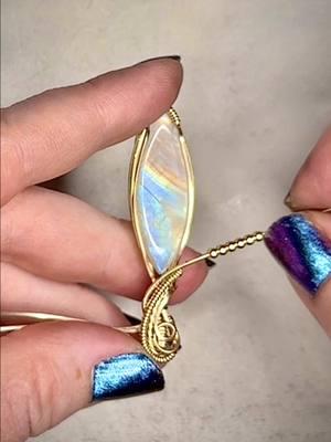 This pretty Moonstone has yellow/orange flashes of color down at the bottom and I thought it would look so good in the gold fill wire.  Did I make the right choice?? 🩵💛 #fyp #foryou #handmade #wirewraps #wirewrap #wirewrapping #wirewrappedjewelry #wirewrappedcrystals #crystals #jewelrydesign #fairyvibes #elven #elvenjewelry #luxuryjewelry #jewelrydesigner #moonstone #rainbowmoonstone #moonstonejewelry 