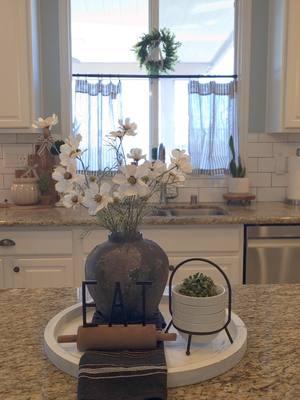 My kitchen window got a fresh look. I added new cafe curtains, mini topiaries, and a garland.  I love looking at it while I'm doing dishes. It makes me feel like I'm in a little café in Paris.  Anyone else obsessed with decorating their kitchen windows?  #kitchen #cafecurtains #cottagekitchen #kitchendecor #kitchenwindow #cottagefarmhouse #kitchencounter #countrycottagestyle #cottagecore #cozyhome #nancymeyers #cottageaesthetic #homefinds 