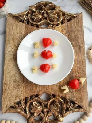 Cupid’s Bow & Arrow🍅🧀 🏹💘 Using just two ingredients, you can create the cutest Valentine’s Day garnish. Whether you place it on a charcuterie board for a little festivity, or in your kids lunchbox - these are “aimed” to please, no pun intended. 😉🥰 . Using my favorite @pamperedchef paring knife, I simply took a grape tomato and sliced it diagonally the long way. Rotate the two pieces slightly to create a heart shape and place aside. Next, take a piece of string cheese and slice one end diagonally on each side. Then cut the tip off - this is the arrowhead. Lastly, cut the other end off the cheese and slice a small arrow shape and discard the piece you cut off. This is the back of the arrow. Assemble on a toothpick as shown and that is it! Super cute and easy! What is your favorite Valentine’s Day snack?  . . ✨Follow along for more Charcuterie Boards, Midwest Accents, Tutorials, Recipes & more! .  . 📬 : TheBoardLoon@gmail.com  . 💻 : www.TheBoardLoon.com . . @TheBoardLoon on TikTok & Facebook . #charcuterieboard #Recipe #charcuterie #theboardloon #cheeseboard #cheeseplatter  #charcuterieworkshop #cheese #appetizer #fyp #thisishowipamperedchef #valentines