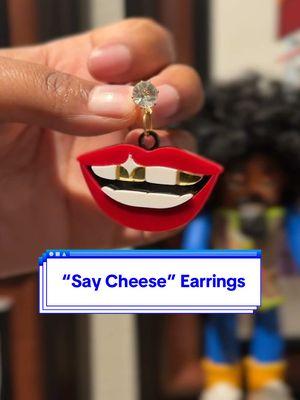 👄 Red lips, a bright smile, and two gold teeth— the "Say Cheese" earrings bring the drip without the dentist trip 🦷 #valentinesdaygifts #giftsforher #statementearrings #earringsoftheday #earrings #goldteeth #SmallBusiness #blackart #acrylicearrings #womanowned #blackowned #blackbusiness #blackhistorymonth  #statementjewelry 