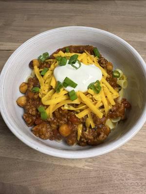 Homemade Chili - The only real debate is are you adding noodles or not??  Let me know in the comments! Ingredients: 1lb Ground Beef 1 Onion (or shallot), diced 3 Cloves Garlic, minced 1 Jalapeño, chopped Black Beans Kidney Beans Garbanzo Beans 15oz Diced Tomatoes (I like fire roasted!) 15oz Tomato Sauce 15oz Tomato Juice 3t Chili Powder 1t Cayenne Salt and Pepper to Taste (around 2t each) Shredded Cheese Sour Cream Green Onion Noodles! In a pot, add the beef and break into chunks. Add the onion, and garlic and cook for around 5 mins. Add the beans, jalapeño, tomatoes, tomato sauce, tomato juice, and spices. Bring to a boil, cover and simmer all afternoon! Make sure to check in and add spices as needed. Build and eat! Enjoy!! #chili #chiliseason #soup #soupseason #soupforthesoul #warmmeup #yummm #explore #fyp 