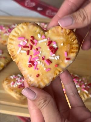 Heart shaped pop-tarts 💗 Ingredients  - 1 package of store bought pie crust - raspberry jam (you can also use strawberry, blueberry, etc.) - 1 egg; beaten for egg wash  Pop tart glaze  - 1 & 1/2 cups of powdered sugar  - 1/2 tsp of vanilla  - 2 tbsp of milk or water - optional; food coloring to make color pink Other - optional; sprinkles Preheat oven to 400F Start by rolling out one pie crust onto a cutting board (w/ flour if needed) or a clean surface. Using a heart shaped cookie cutter, cut out as many hearts as you can. Place on a lined baking sheet with parchment paper. Repeat steps with other pie crust except you can leave those hearts on the cutting board or surface your cut them out on.  Get your jam and place about 1/2 to 1 tbsp of jam in the center then place another one of the hearts on top. Seal edges with a fork. Repeat until all pop tarts are made.  Then with a fork also poke holes at the top of the pop tart. Then take your egg wash and brush on the entire top of each pop tart. Place in the oven to bake for 10-12. Once done let cool and if you have a cooling rack place them on there to cool.  Meanwhile, mix all ingredients together for the glaze and set aside.    Once pop tarts are cooled, add on glaze and sprinkles. Then enjoy! #valentinesdayrecipes #valentinesdaystreats #heartshapedtreats #homemadepoptarts #kidfriendlysnacks ##kidfriendlytreats ##valentinesdaydesserts ##galentinesdayfoodideas ##galentinesdayparty ##fyp. ##trending  ##viral