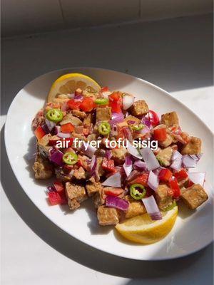 Air Fryer Tofu Sisig  You don’t have to go to the Filipino market to make Filipino food. This is a series to prove that Filipino Food can be accessible by creating dishes with ingredients that are not from the Filipino or Asian market today’s menu is air fryer tofu sisig with ingredients from Target.  Ingredients (serves 2) Tofu - 1 block of tofu, pressed - 2 Tbsp cornstarch - 1 tsp garlic powder - 1/2 tsp pepper - 2 Tbsp avocado oil  Skillet - 1 Tbsp oil, neutral - 1 small red onion - 1/2 small bell pepper - Chilis, i.e serrano or per preference Sauce - 1/4c mayo - 1-2 tsp soy sauce - 1 Tbsp oyster sauce - Zest of 1/2 lemon - Juice of 1/2 lemon - Salt and pepper, to taste Directions 1. In a mixing bowl, combine tofu with cornstarch, garlic powder, pepper, and avocado oil. Gently toss to coat evenly. 2. Lightly oil the bottom of the air fryer basket to prevent sticking. Air fry the tofu at 400°F (200°C) for 10 minutes. Shake the basket to stir the tofu, then air fry for an additional 10 minutes or until crispy. Set aside. 3. Heat oil in a skillet over medium heat. Add most of the red onions, bell peppers, and chilis, reserving a small amount for garnish. Sauté until the vegetables are soft. 4. Add the air-fried tofu to the skillet. Mix well and season with salt and pepper to taste. 5. In a bowl, combine all sauce ingredients. Pour the tofu and vegetable mixture into the sauce and toss to coat evenly. 6. Garnish with the reserved onions, bell peppers, and chilis. Serve with extra lemon slices on the side. #krizkitch #sisig #tofusisig #filipinorecipes #tofurecipes #filipinofood #pulutan 